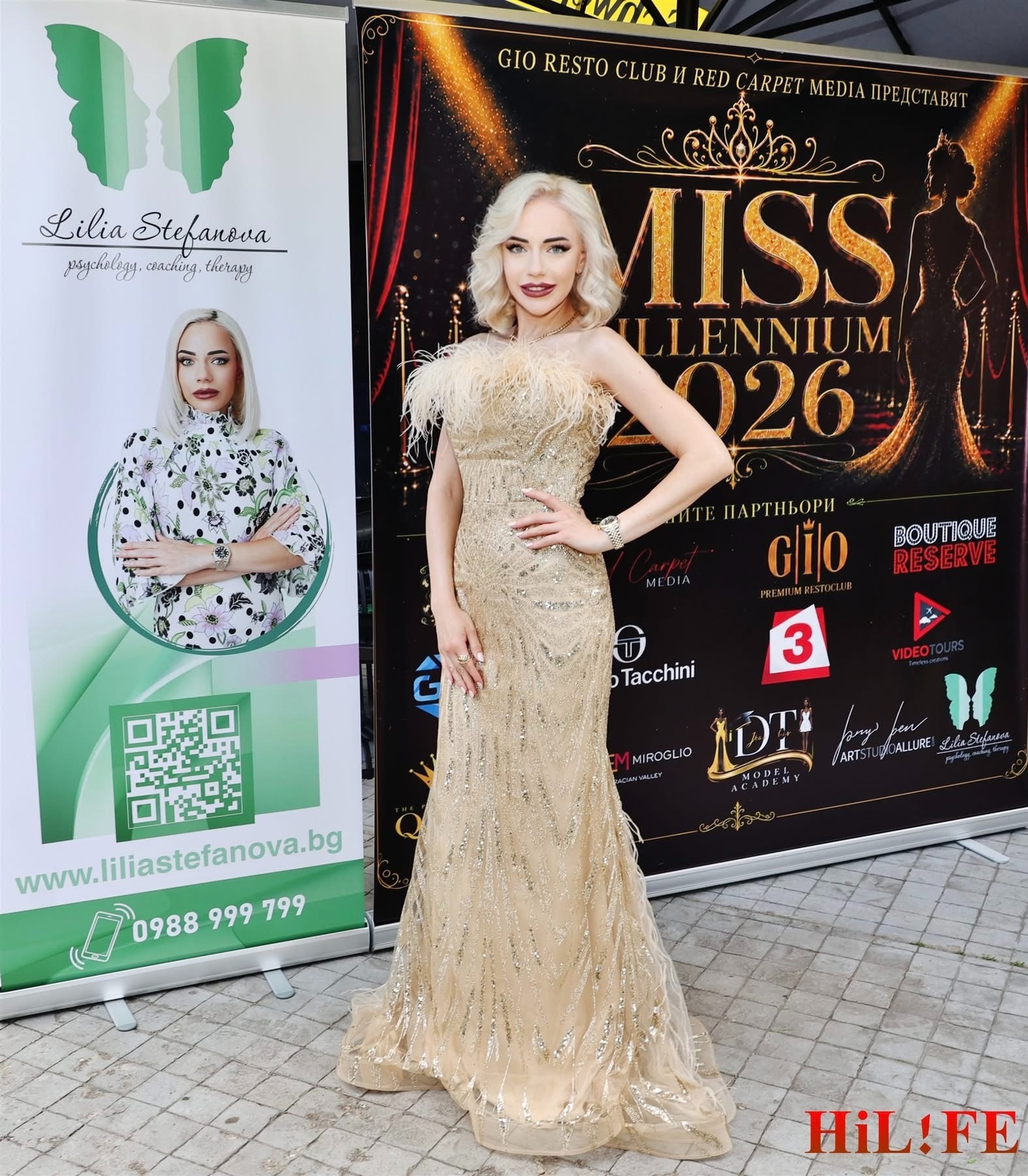 Woman in a gold sequin evening gown posing with hand on hip beside two promotional banners; one banner shows a green logo and portrait, the other reads MISS MILLENNIUM 2026.